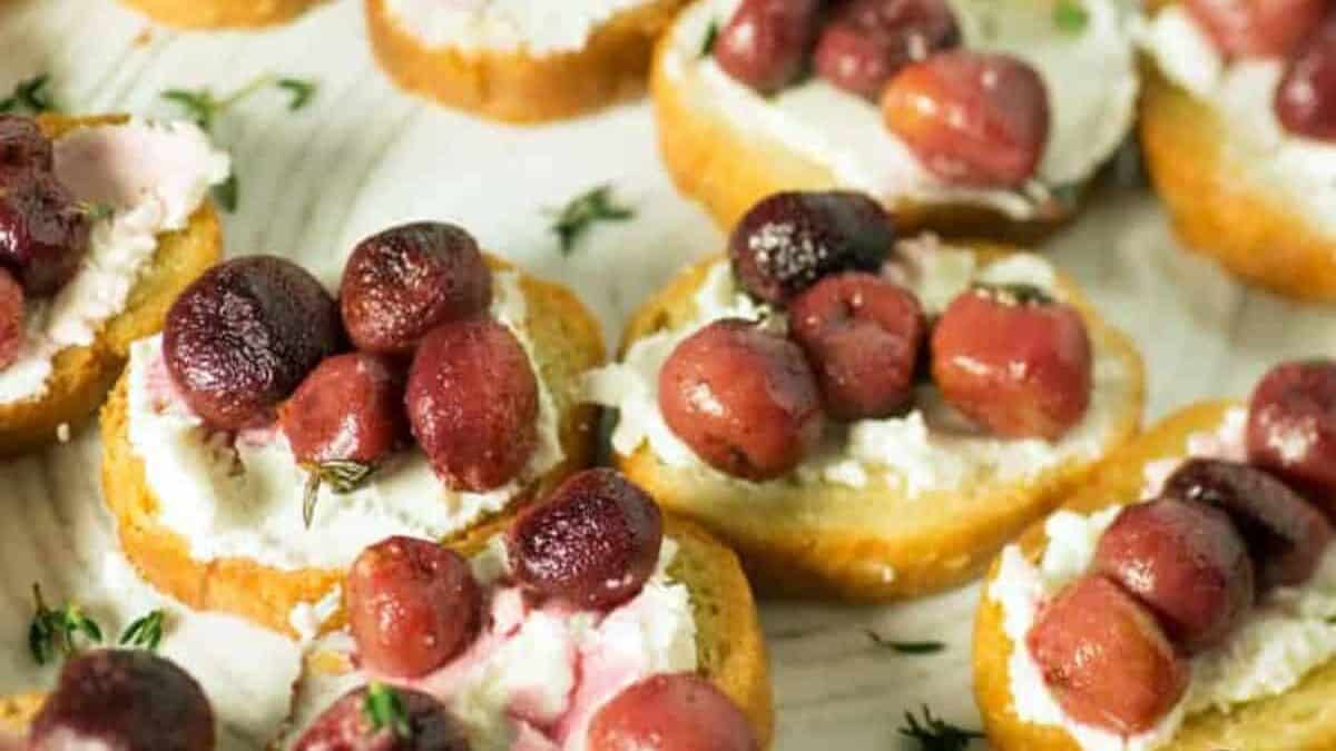A platter of roasted grapes on bread rounds.