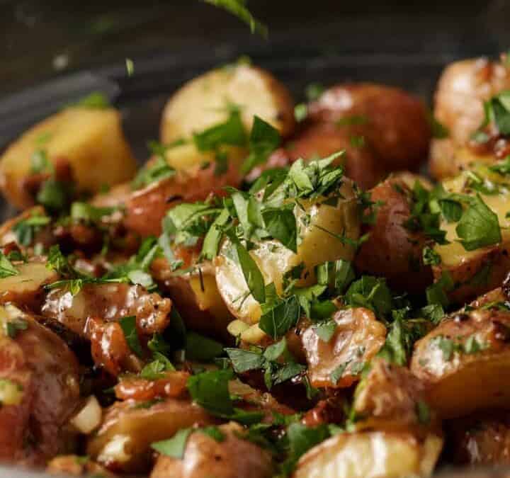 Parsley being sprinkled over warm potato salad