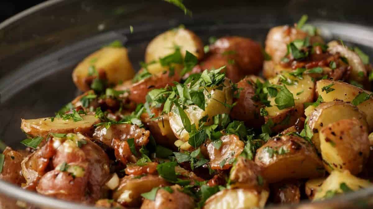 Parsley being sprinkled over warm potato salad