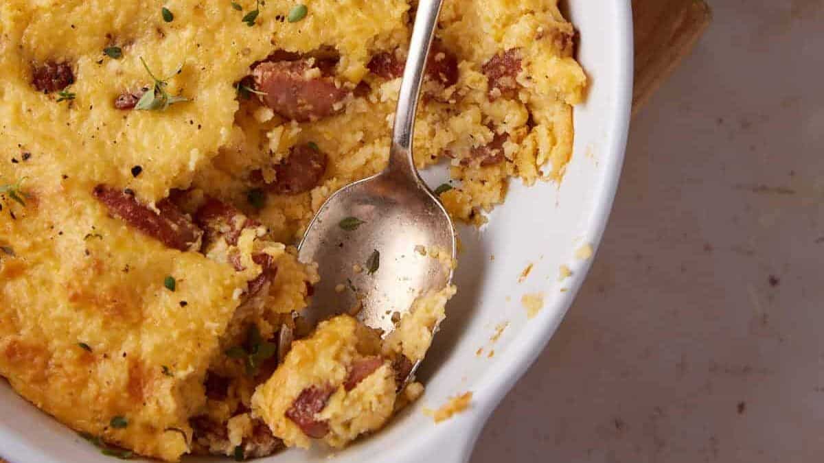 A casserole dish of grits with a serving spoon.