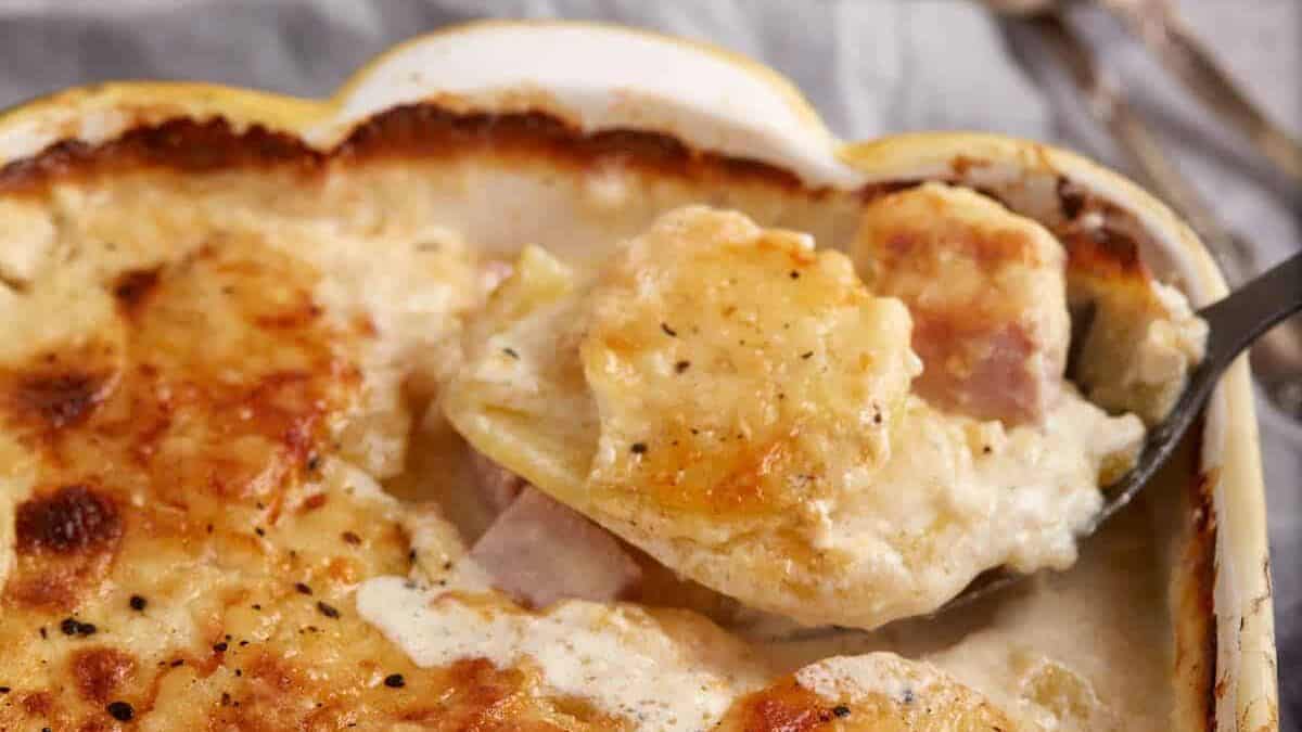 A serving spoon removing some potato and ham casserole.