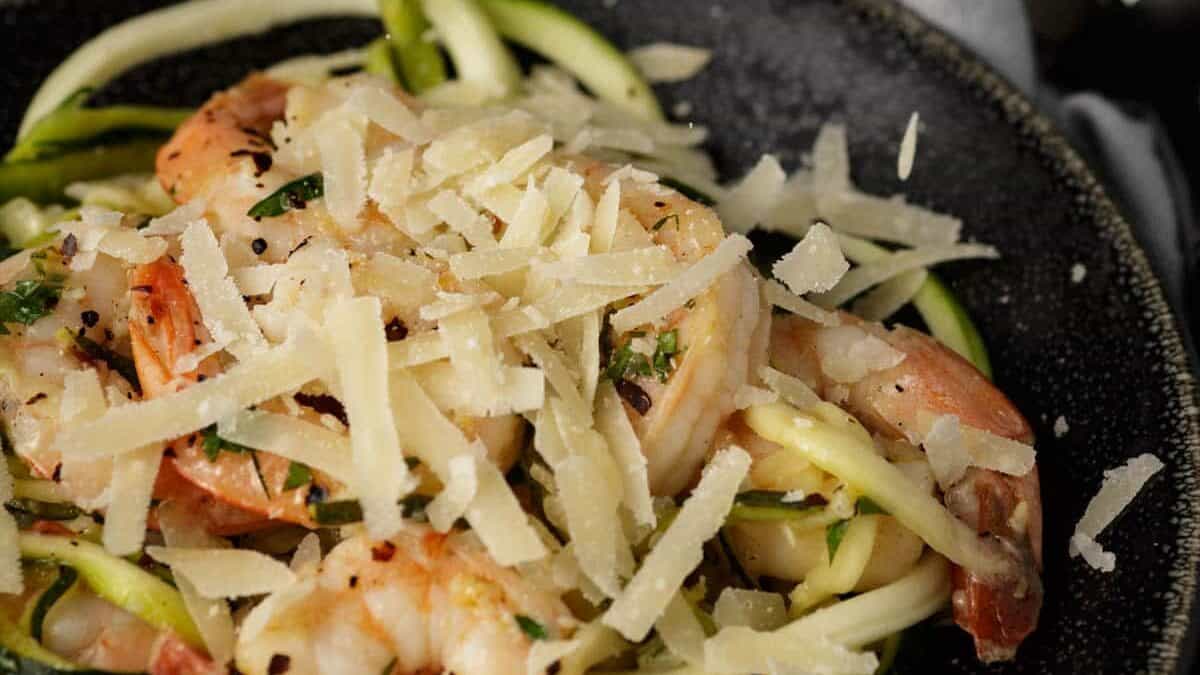 Cheese dropping onto a plate of shrimp scampi