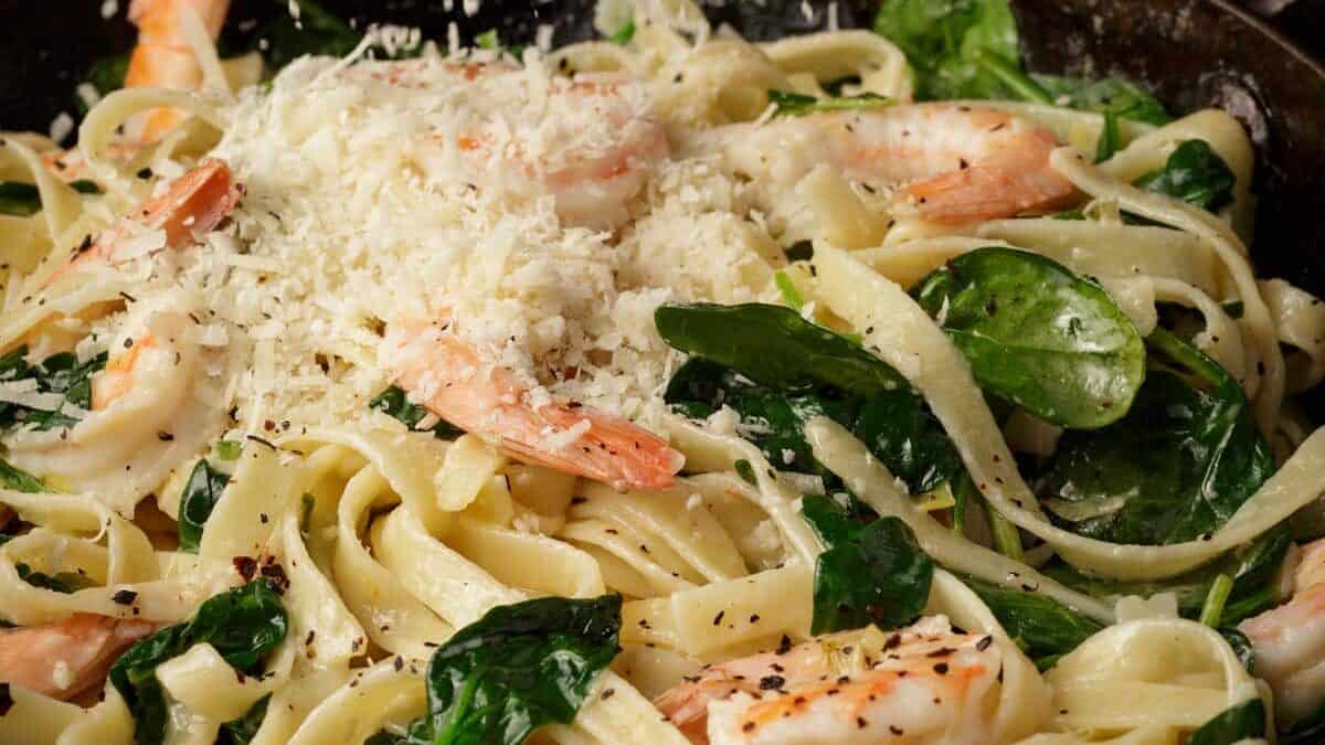 Parmesan being added to shrimp and pasta.