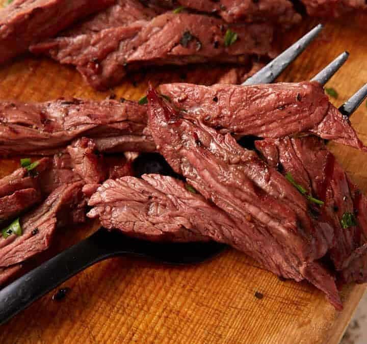 Marinated skirt steak grilled and sliced on a cutting board.