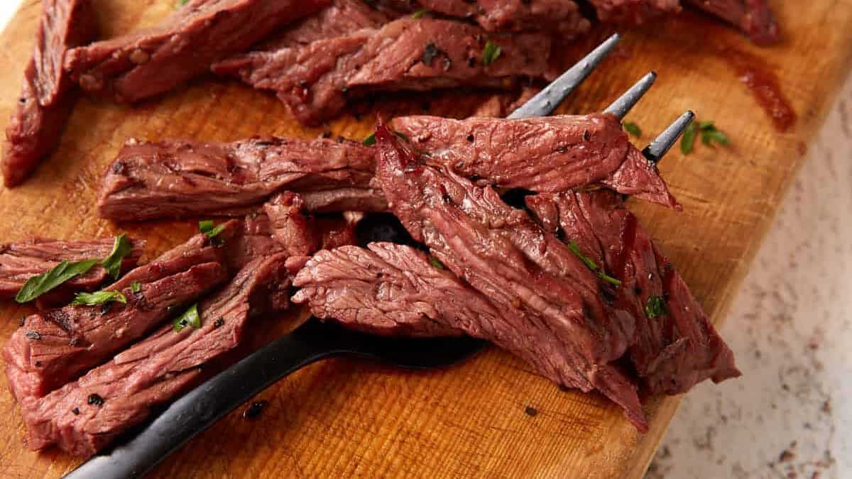 Marinated skirt steak grilled and sliced on a cutting board.