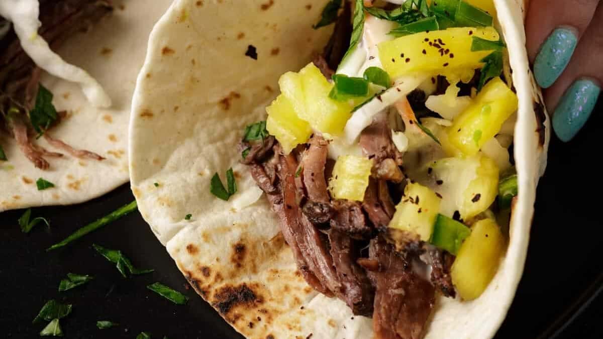 Beef tacos made with shredded beef and pineapple salsa.