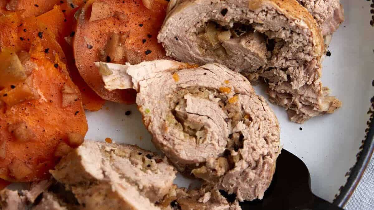A serving fork removing slices of slow cooked pork tenderloin.