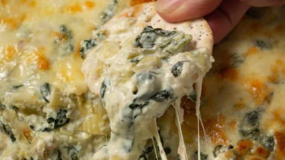 A scoop of spinach artichoke dip on a cracker.