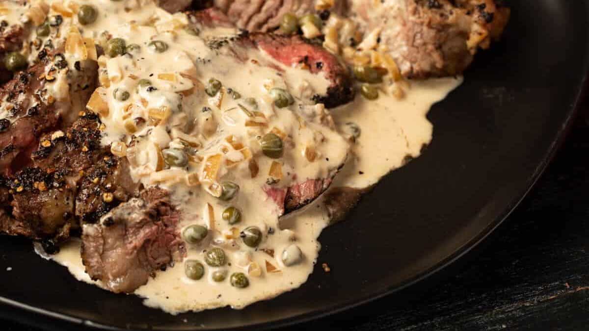 Steak au Poivre on a black platter with a bottle of Cognac.