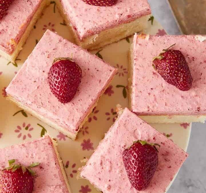 A platter of cut squares of strawberry cake.