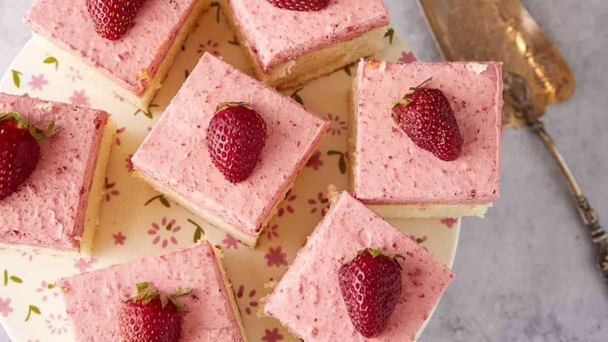 A platter of cut squares of strawberry cake.