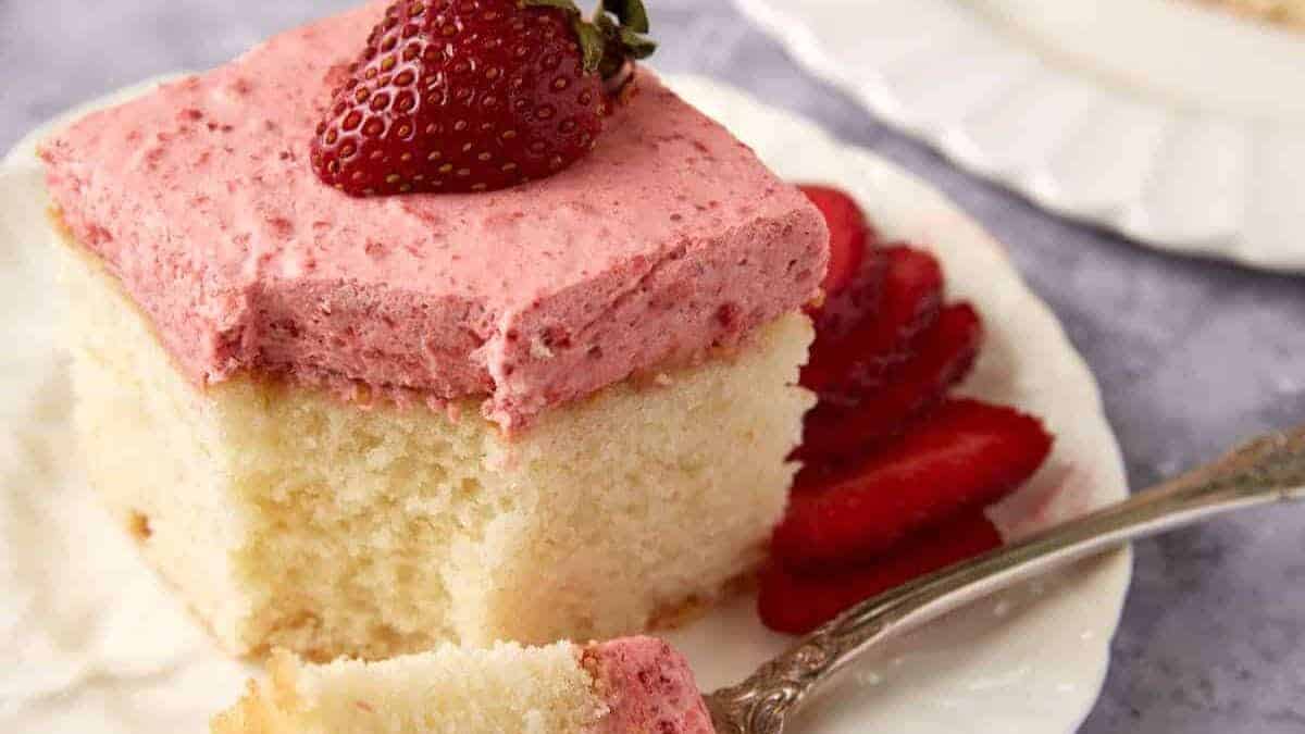 A piece of strawberry mousse cake with a bite on a fork.