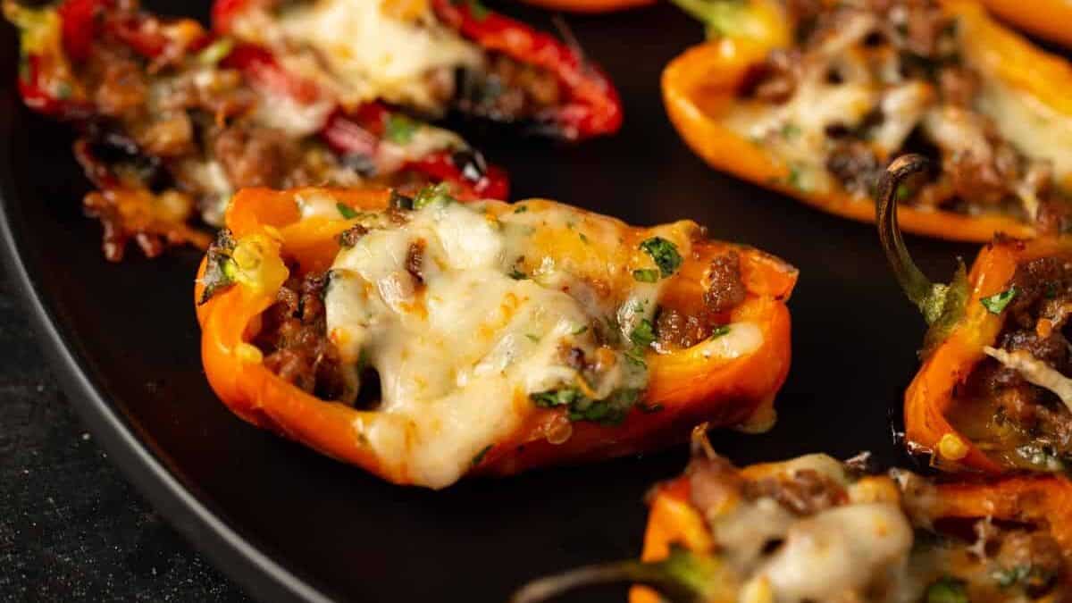 A black platter full of mini stuffed peppers.