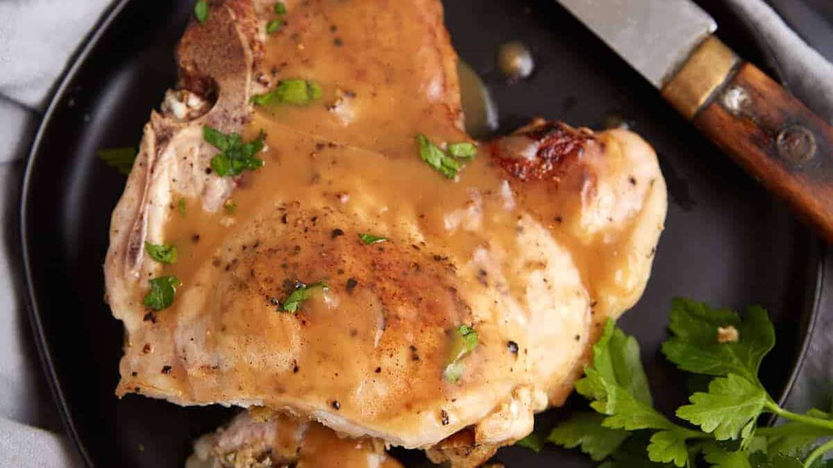 A stuffed pork chop on a plate covered in gravy.