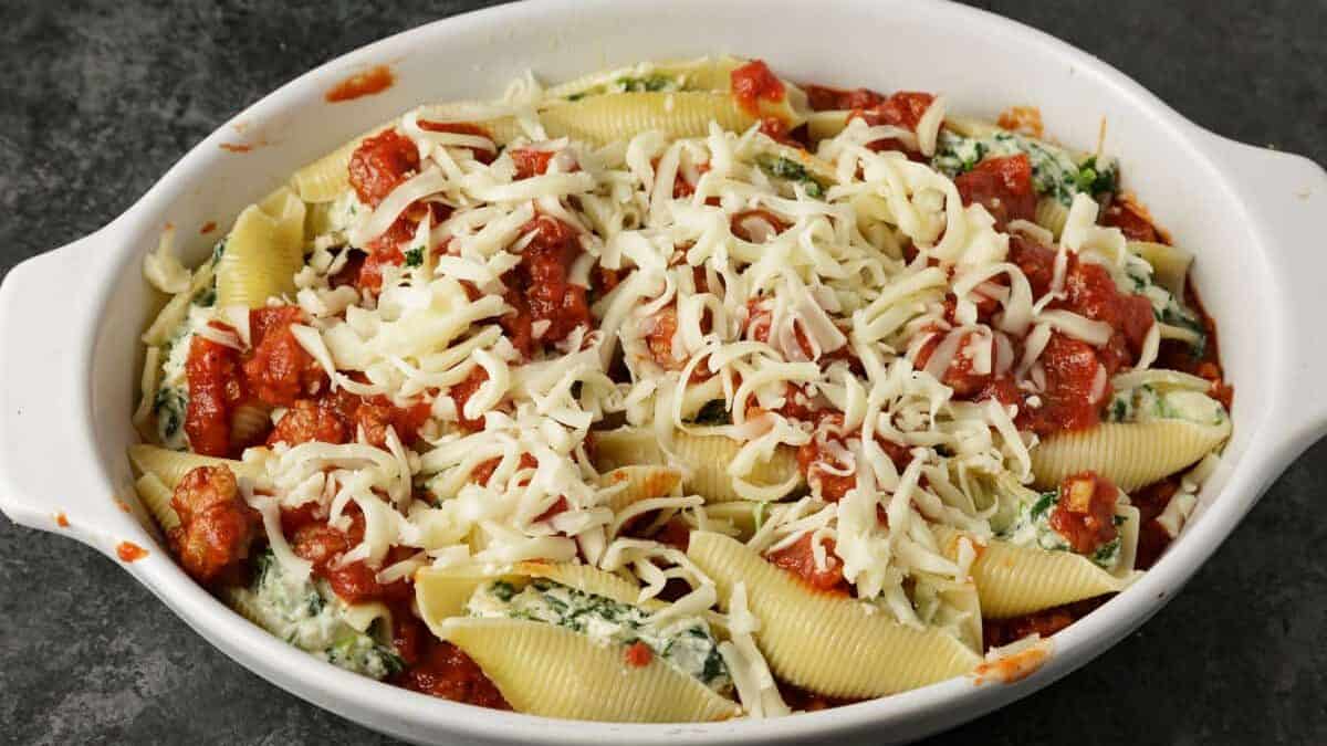 A baking dish of stuffed shells covered with cheese before it is baked