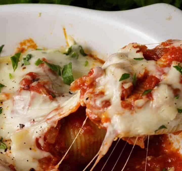 A stuffed shell being removed from a baking dish