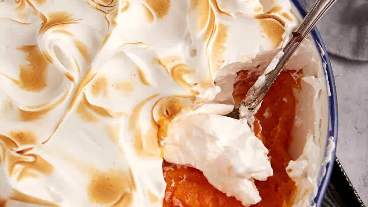 A spoon full of marshmallow topped sweet potato casserole.