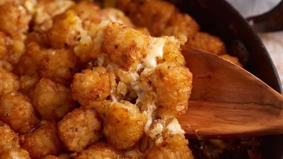 A wooden spoon in a skillet of tater tot casserole.
