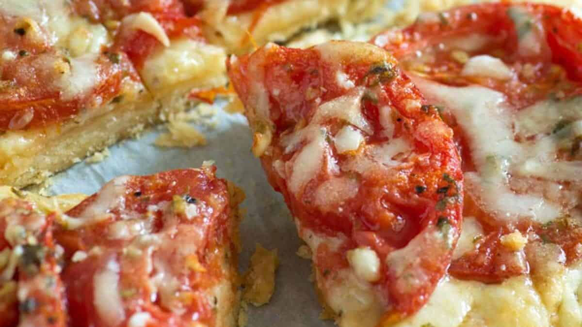 A slice of a tomato tart on parchment paper.