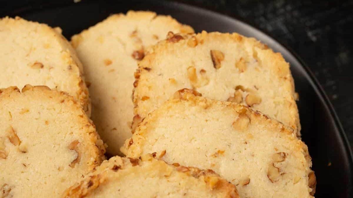 Walnut shortbread cookies on a plate next to a cup of tea.