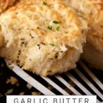 A garlic roll being removed from a skillet.