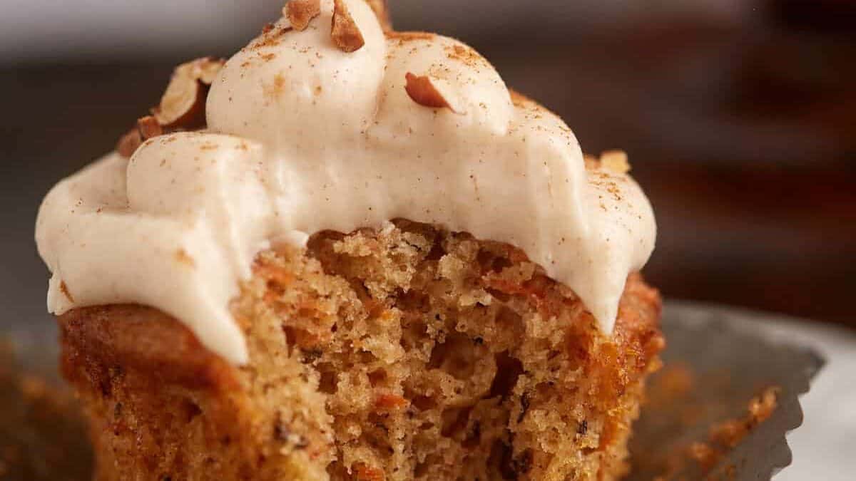 A bite taken out of a carrot cake cupcake.
