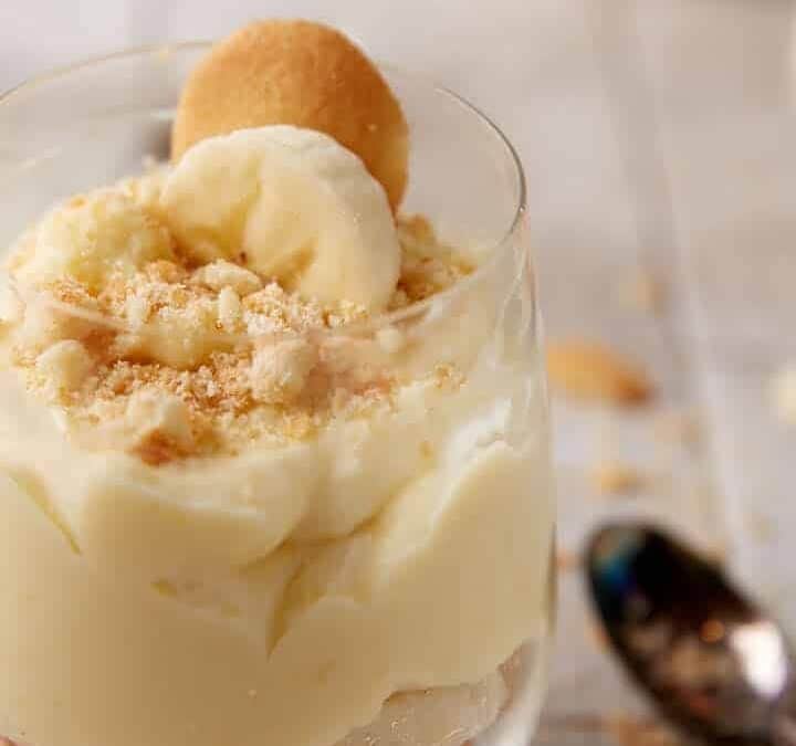 A glass of banana pudding with a slice of banana on top.