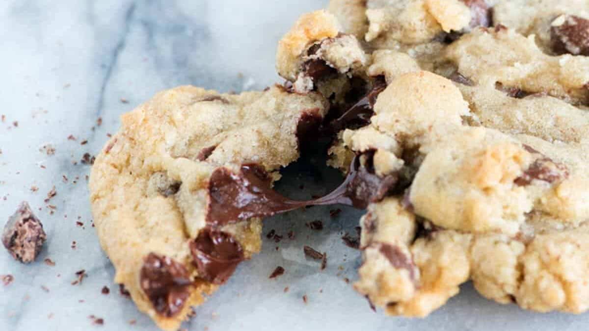 A single chocolate chip cookie with a piece broken off.
