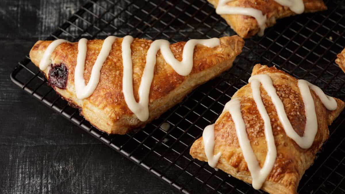 Cherry turnovers on a cooling rack with frosting.