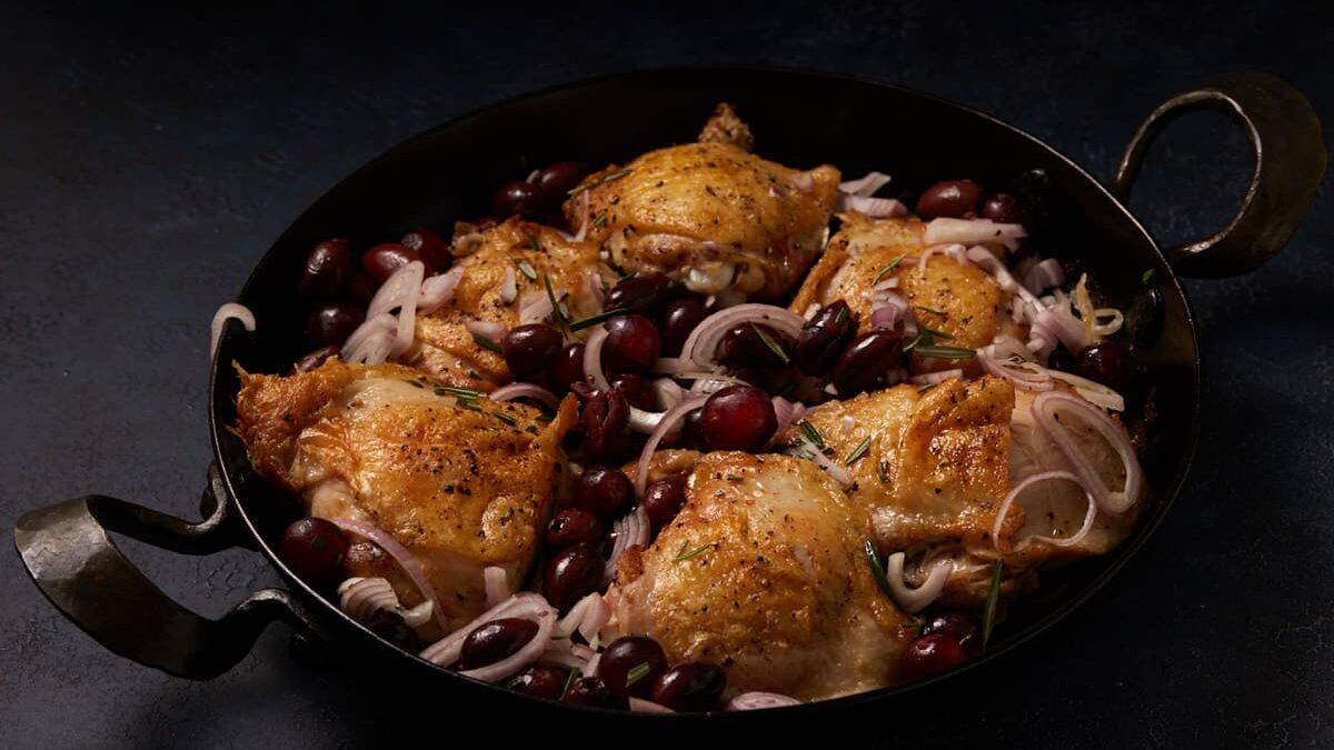 Chicken in a skillet before being baked in the oven.