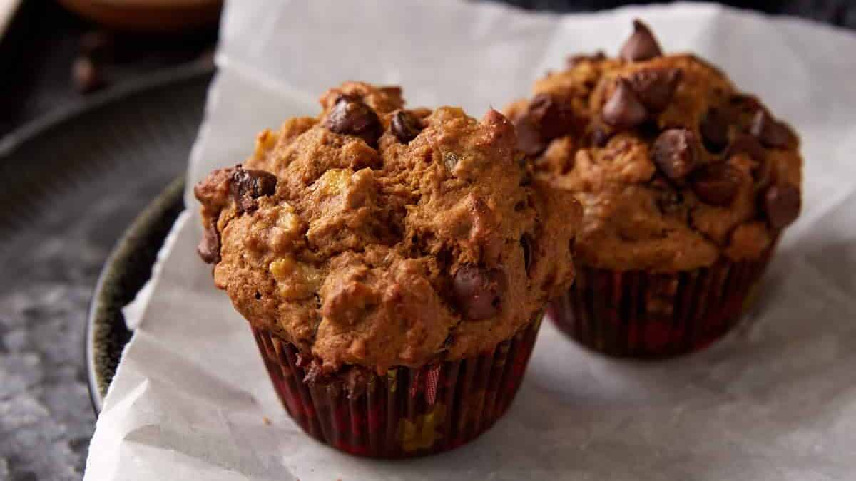 Two banana chocolate chip muffins on a plate with parchment paper.