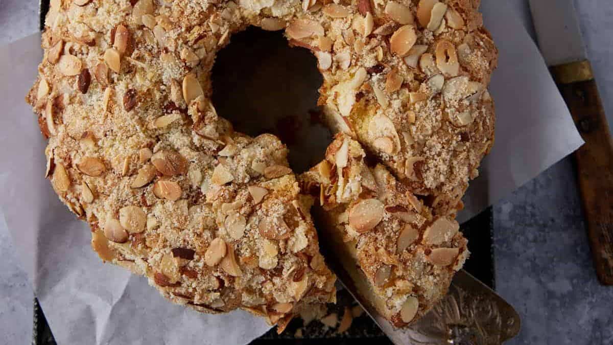 A sliced cake next to coffee cups.