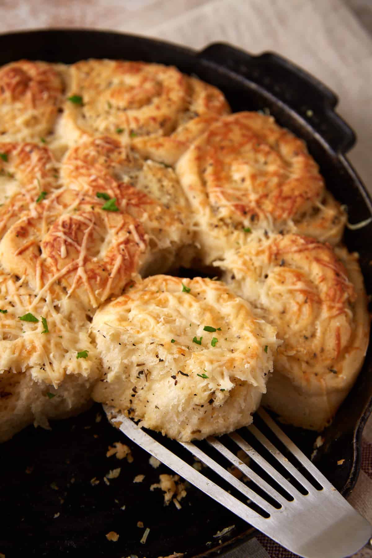 A garlic roll being removed from a skillet.