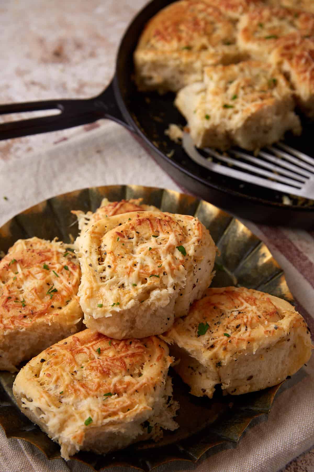 Garlic butter rolls on a platter next to a skillet.