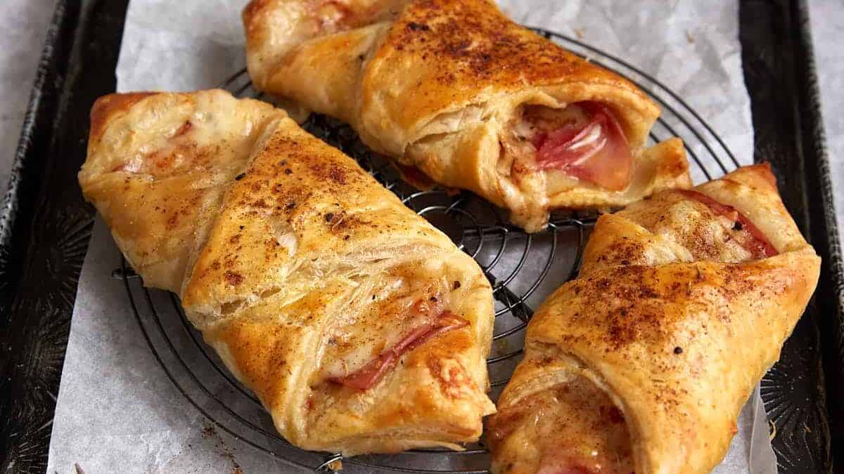 Ham and cheese puff pastries on a cooling rack.