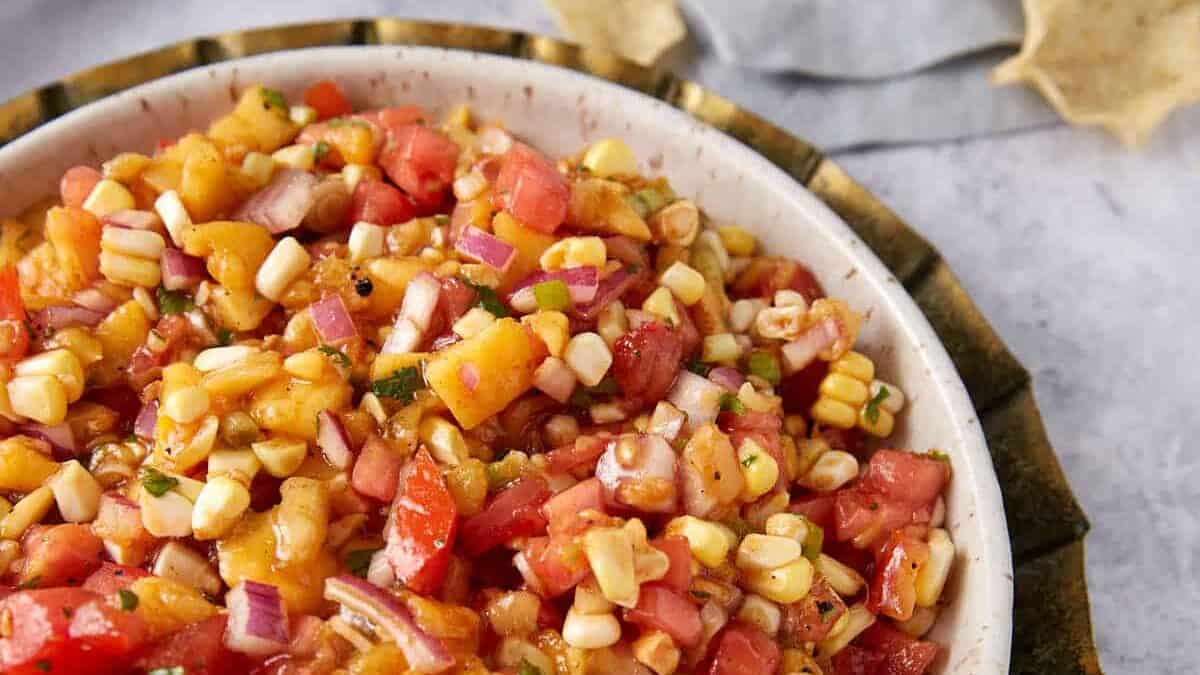 A bowl of easy-to-make salsa with the perfect balance of peaches, tomatoes, and corn.