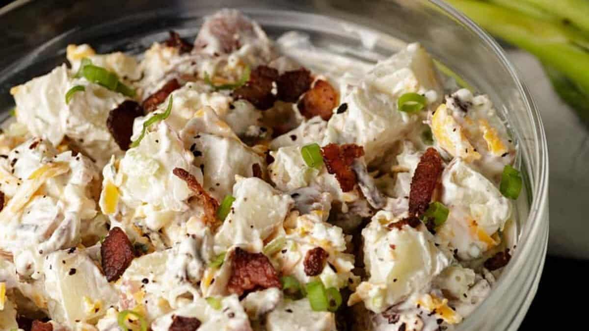 Southern style Ranch potato salad in a glass bowl next to green onions.