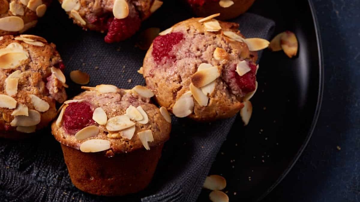 raspberry and white chocolate muffins next to a bowl of honey butter.