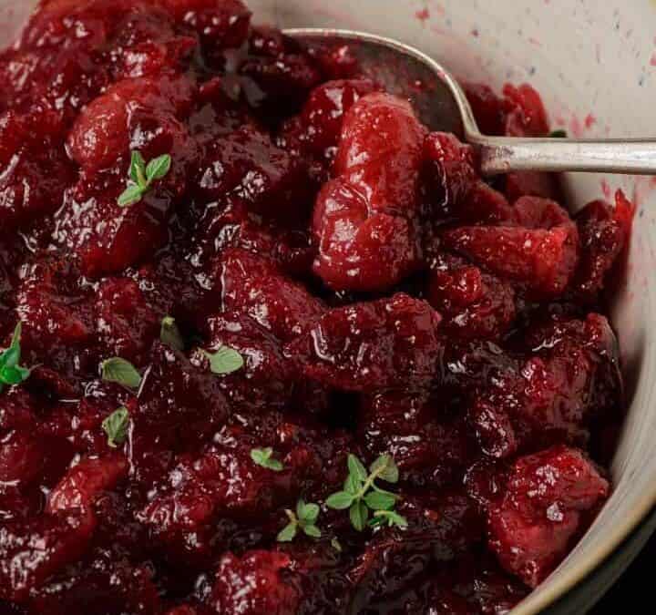 A white bowl of cranberry sauce with grapes.