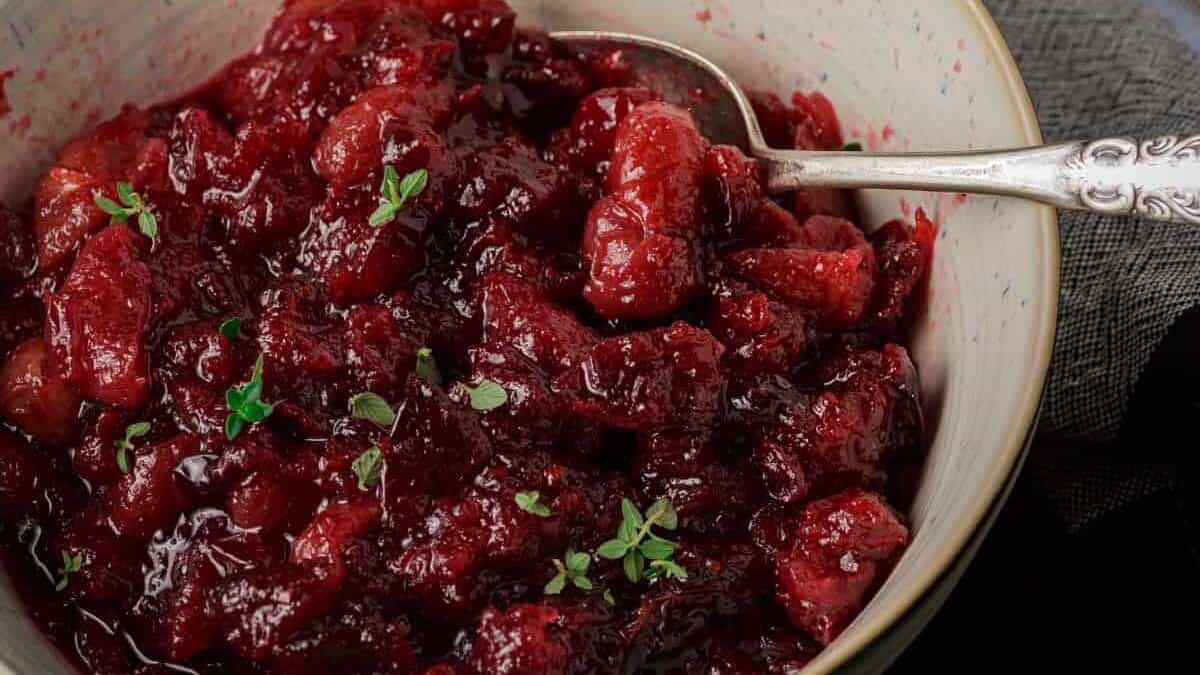 A white bowl of cranberry sauce with grapes.