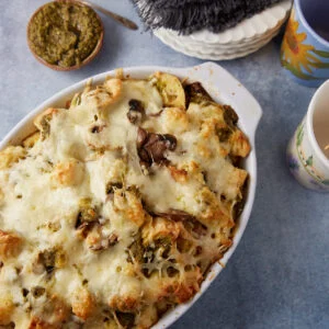 Baked bread pudding with mushrooms and pesto in a casserole dish.