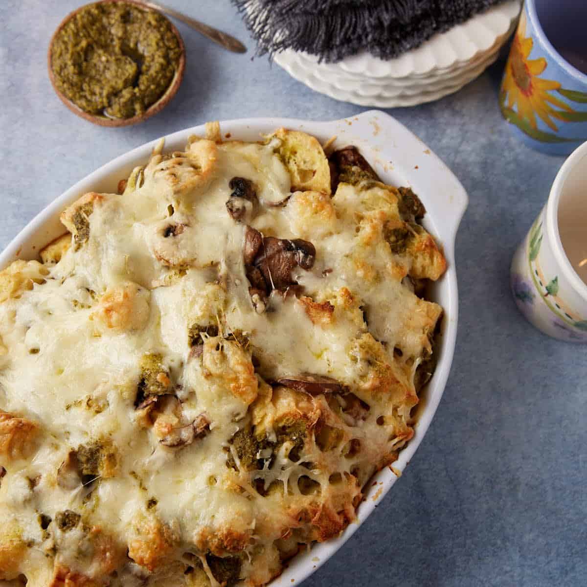 Baked bread pudding with mushrooms and pesto in a casserole dish.