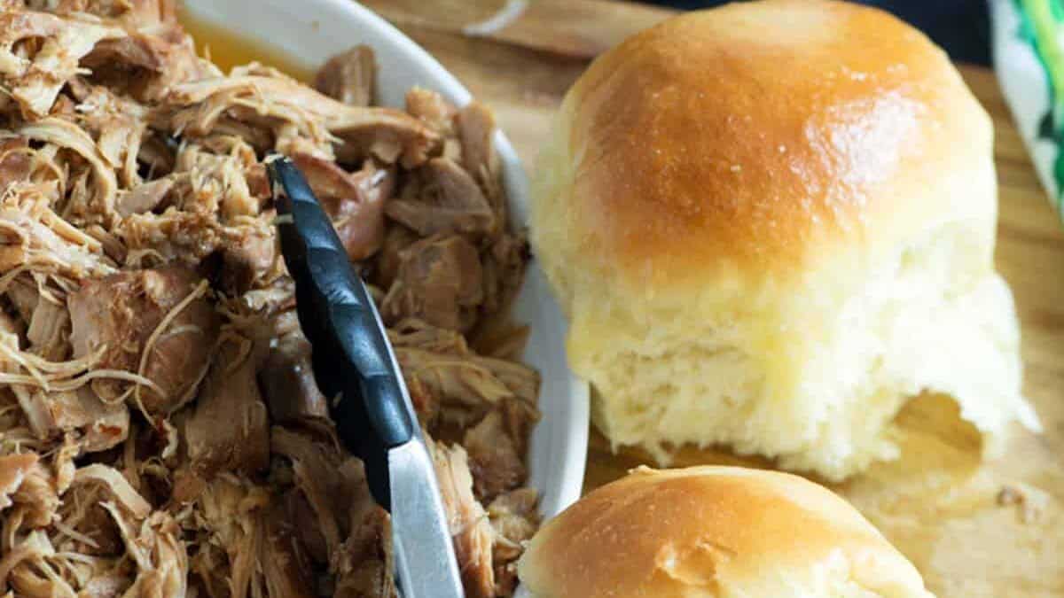 Slow cooked chicken on a platter next to two sliders.