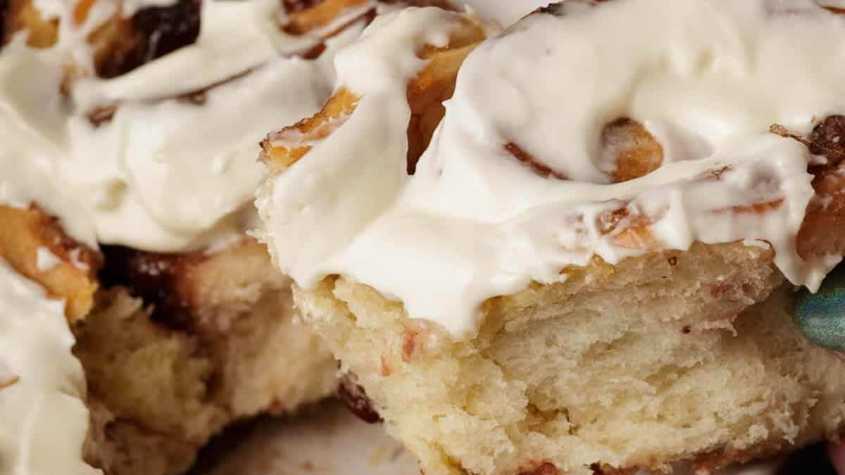 Close-up of soft, fluffy cinnamon rolls topped with creamy white icing, highlighting their swirled texture and gooey layers—an irresistible treat for lovers of cinnamon desserts.