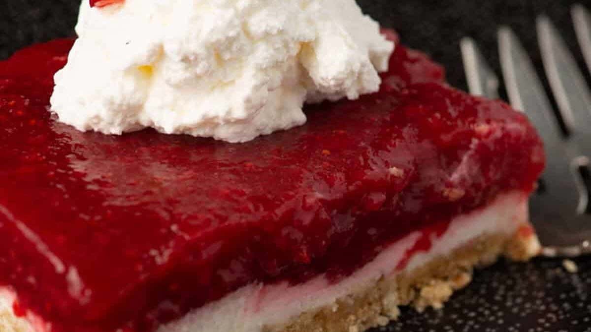 A serving of strawberry pretzel salad with topped with whipped cream