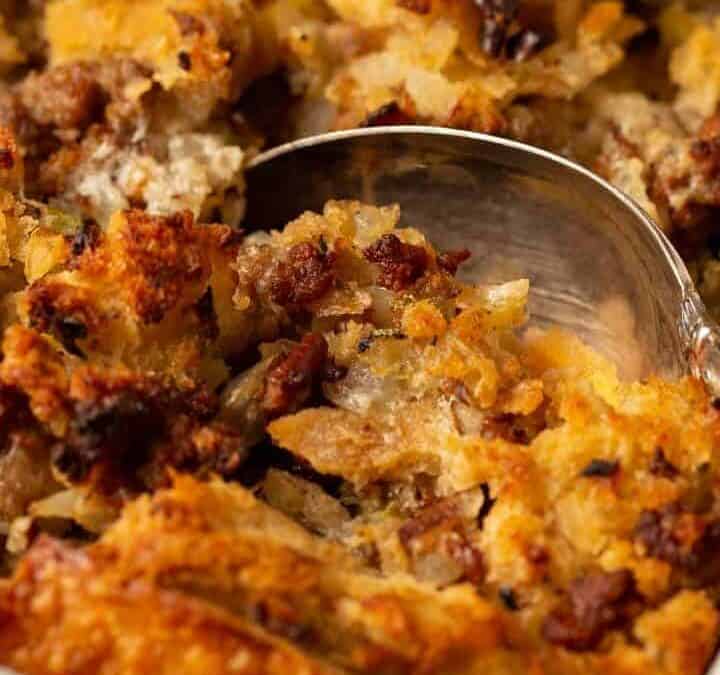 A casserole dish of baked stuffing with a serving spoon.