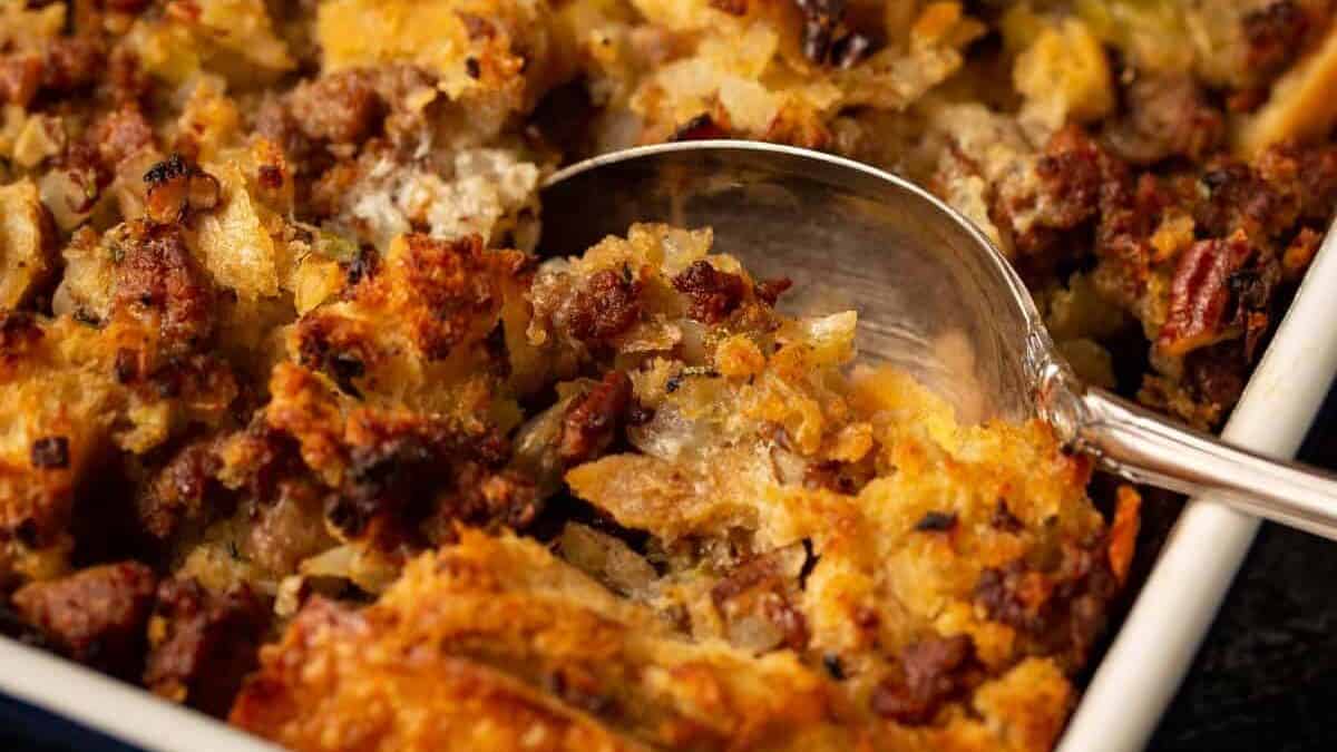 A casserole dish of baked stuffing with a serving spoon.