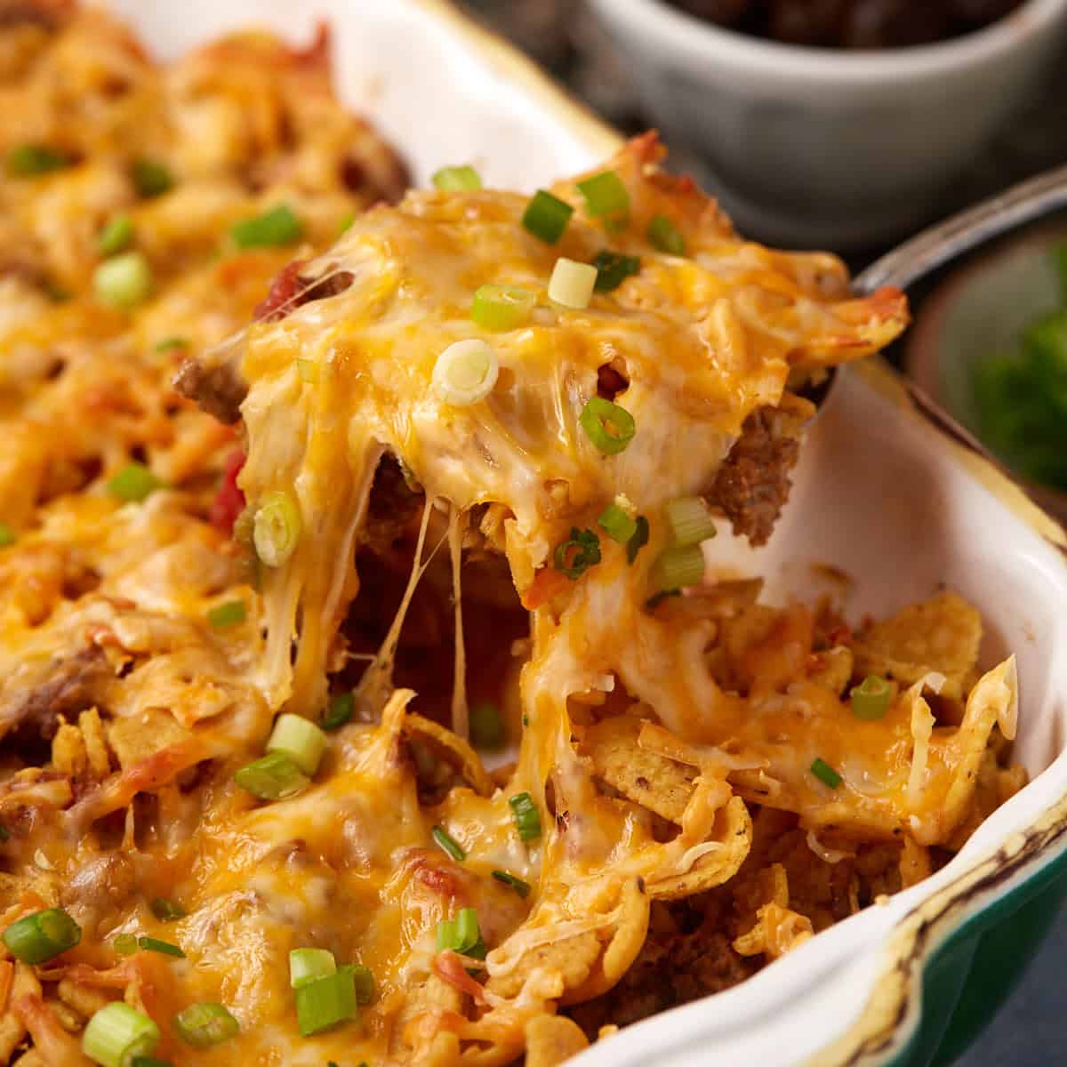 A cheesy spoon full of taco casserole with Fritos.