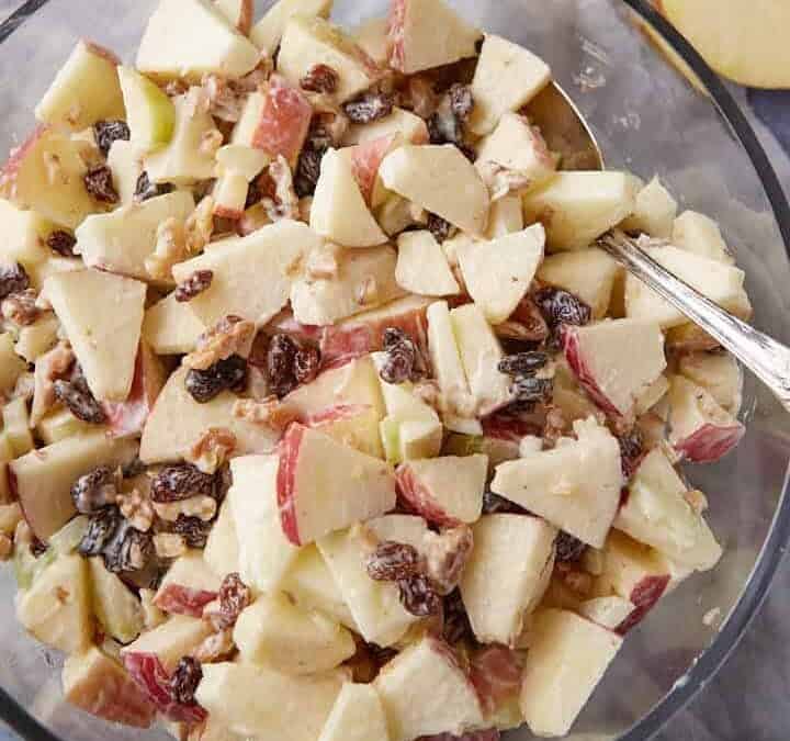 A bowl of apple salad with a serving spoon.