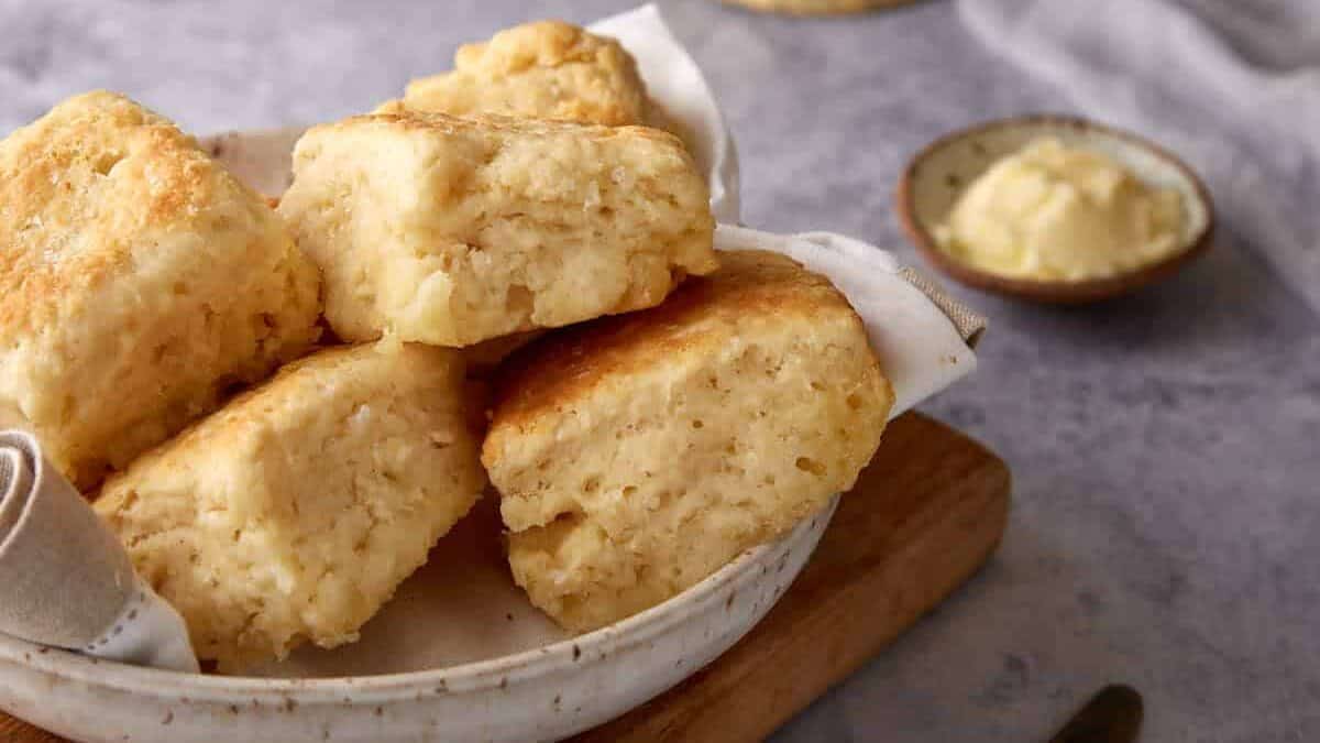 A bowl of 7 UP biscuits next to a dish of butter.